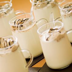 there are many pitchers of milk with whipped cream in them on the table and one pitcher is filled with liquid