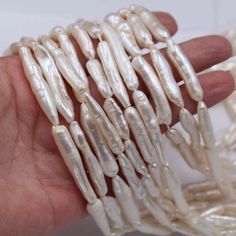 a hand is holding some white beads in it's palm, and there are several rows of them