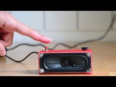 a hand is pointing at an old fashioned radio on a wooden table with wires in the background