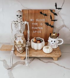 a wooden tray topped with halloween decorations and skeleton figurines next to a sign that says my blood type is pumpkin spice