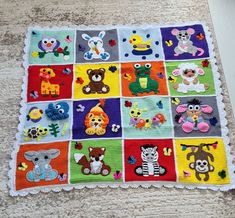 a crocheted blanket with many different animals and letters on it, sitting on the floor