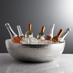 a silver bowl filled with bottles of wine on top of a white marble countertop