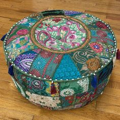 a colorful round ottoman sitting on top of a wooden floor