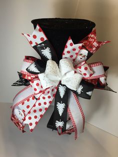 a black hat with red and white polka dots on the top has a large bow attached to it