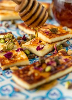 honey being drizzled over small squares of food on a blue and white plate