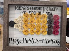 a framed sign that says teachers change the world one pencil at a time with paper flowers