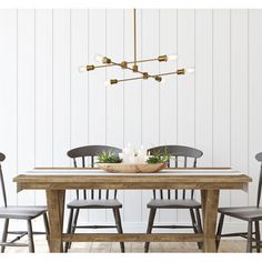 a dining room table with four chairs and a plant on it, in front of a white wall