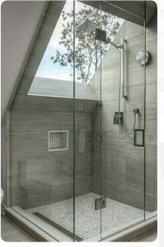 a glass shower door in a bathroom with a skylight on the ceiling and an open window above it