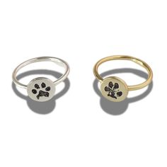 two rings with paw prints on them, one in gold and the other in silver