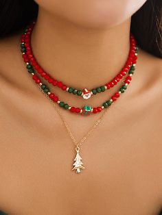 a woman wearing red, green and gold beaded necklace with a christmas tree charm