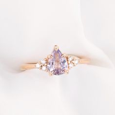 a pink diamond ring with three white diamonds on the band and an oval shaped center stone