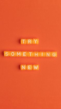 the words try something new spelled with scrabbles on an orange background,