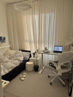 a bedroom with a bed, desk and computer on it's side in front of a window