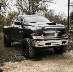 a black ram truck parked on top of a dirt road