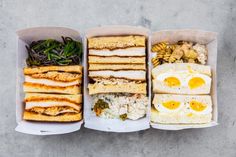 three boxes filled with different types of food on top of a cement floor next to each other