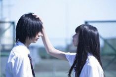 two people standing next to each other with long black hair and ties on their heads