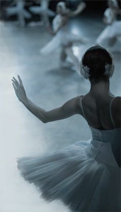 a black and white photo of a ballerina in the middle of a dance class