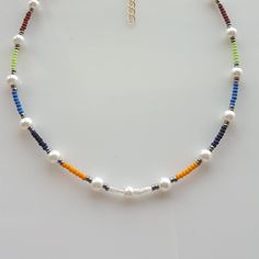 Add a pop of color to your summer wardrobe with this stunning and vibrant colorful seed bead boho necklace. Handcrafted with care, this pearl beaded necklace is the perfect accessory for a casual day at the beach or a fun night out. The rainbow beads add a playful touch, making it a versatile piece for any occasion. This beaded choker necklace also makes a thoughtful gift for her or him, adding a touch of bohemian flair to their jewelry collection. Make a statement with this unique and stylish b Bohemian Summer Letter Beads, Colorful Beaded Necklaces For Beach, Colorful Beaded Necklaces For Vacation With Round Beads, Colorful Beaded Necklaces With Round Beads For Vacation, Colorful Beaded Chain Beads For Beach, Colorful Beaded Chain For Beach, Colorful Round Beads Beach Necklace, Colorful Spacer Beads For Summer, Multicolor Heishi Beads For Summer