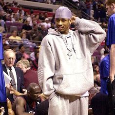 a man standing on top of a basketball court wearing a gray hoodie and black pants