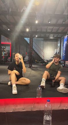 two people sitting on the ground in a gym