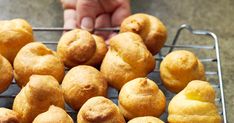 there are many small pastries on a wire rack in front of someone's hand