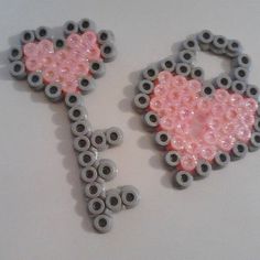 two pink and gray heart shaped beaded keys on a white surface with black eyes