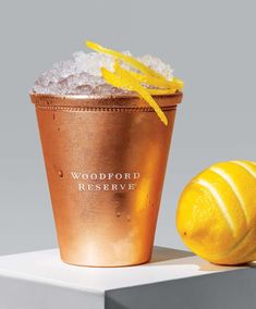 an orange sitting next to a copper cup filled with ice