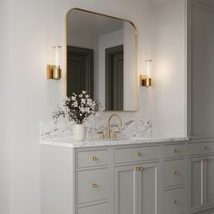 a bathroom with marble counter tops and gold accents on the vanity, along with two large mirrors