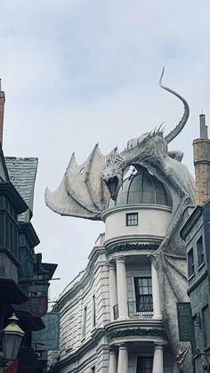 a large white dragon statue on the side of a building next to other tall buildings