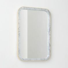 a mirror that is on the wall next to a white wall with a gold frame