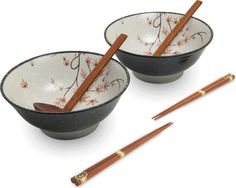 two bowls with chopsticks in them on a white surface