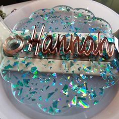 there is a name plate that has confetti on it with the word shannas spelled in cursive letters