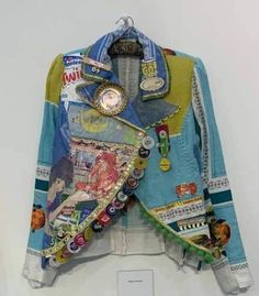 a colorful jacket hanging on a wall with buttons and other things attached to the back