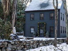 a black house is surrounded by trees and rocks in the foreground with snow on the ground