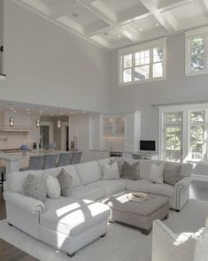 a living room filled with white furniture and lots of windows on top of the ceiling