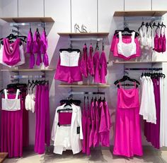 there are many pink and white dresses on display in the store, all hanging up