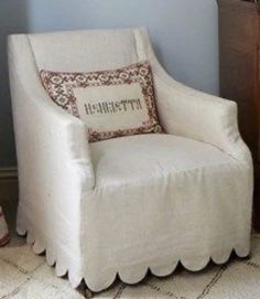 a white chair with a pillow on top of it in front of a wooden dresser