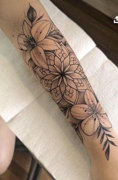 a woman's arm with flowers on it and an arrow tattoo design in the middle