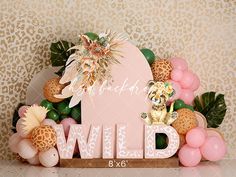 an animal themed backdrop with pink and gold balloons, leopard print wallpaper, and the word wild written in large letters