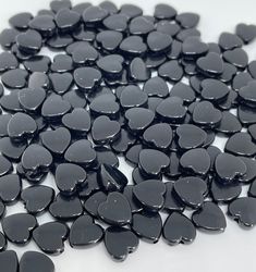 black heart shaped glass beads on a white surface with water droplets all over it,