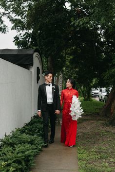 a man and woman in formal wear walking down a sidewalk