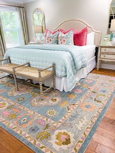 a large bed sitting on top of a wooden floor next to a dresser and mirror