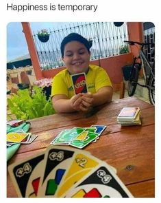 a person sitting at a table with cards and playing cards in front of them that say, happiness is temporary