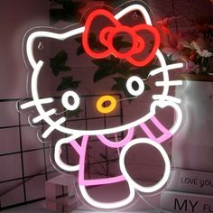 a hello kitty neon sign is lit up in the shape of a cat with a bow on it's head