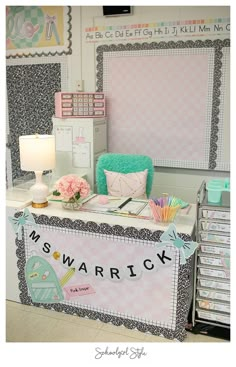 a desk with many items on it in a room that has pink and white walls