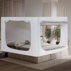 a bed made out of white cardboard with a plant in the corner on top of it