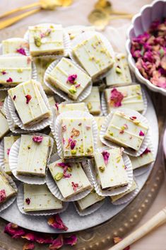 there are many pieces of white chocolate on the plate with pink flower petals around it