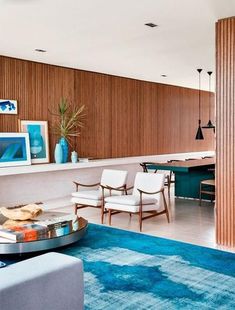 a living room filled with furniture next to a kitchen and dining room table on top of a blue rug