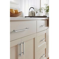 an image of a kitchen setting with white cupboards and stainless steel handles on the drawers