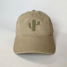 a tan hat with a cactus embroidered on the front and back side, sitting on a white surface